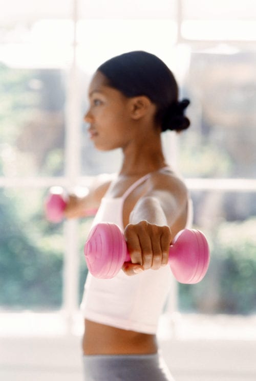 young woman exercising with dumbbells in Capewell Lofts luxury apartments fitness center
