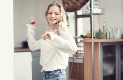 Smiling blond lady dancing at the kitchen