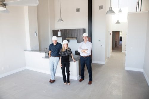 Three members of the Trio Properties team in hardhats standing in the kitchen of a newly renovated Capewell Lofts kitchen
